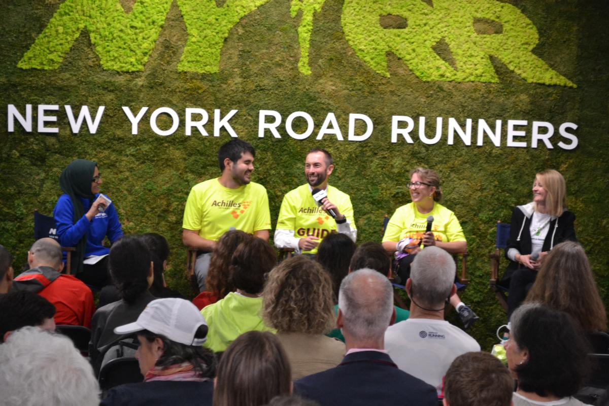 NYRR moderator and Achilles panelists laughing on panel