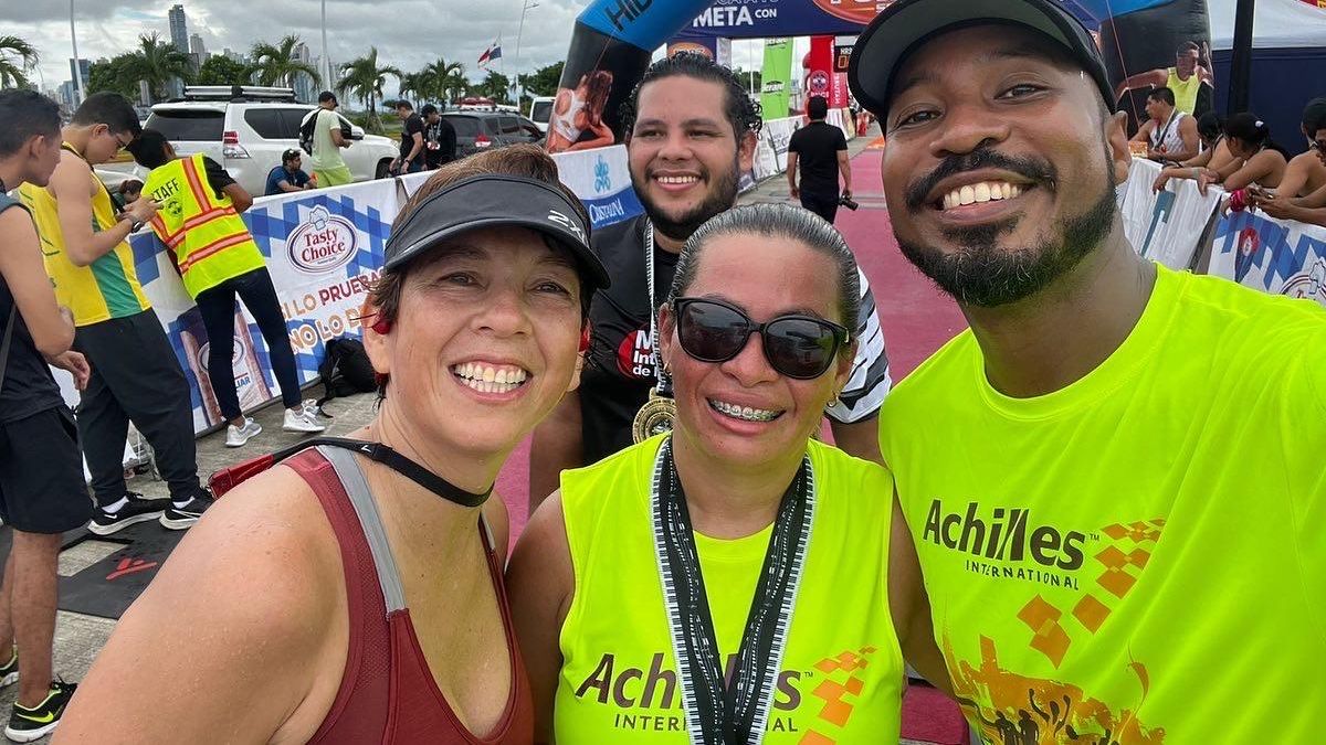 Nayrin at center smiling with her female guide at left and male guide at right at a race finish line