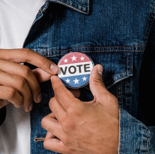 wearable pin that reads "vote"