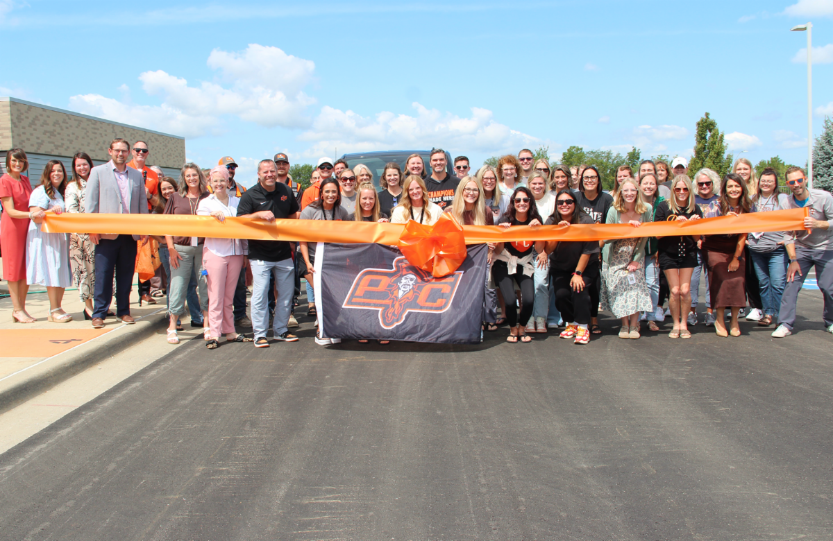 Staff gathering on parking lot with a big orange ribbon