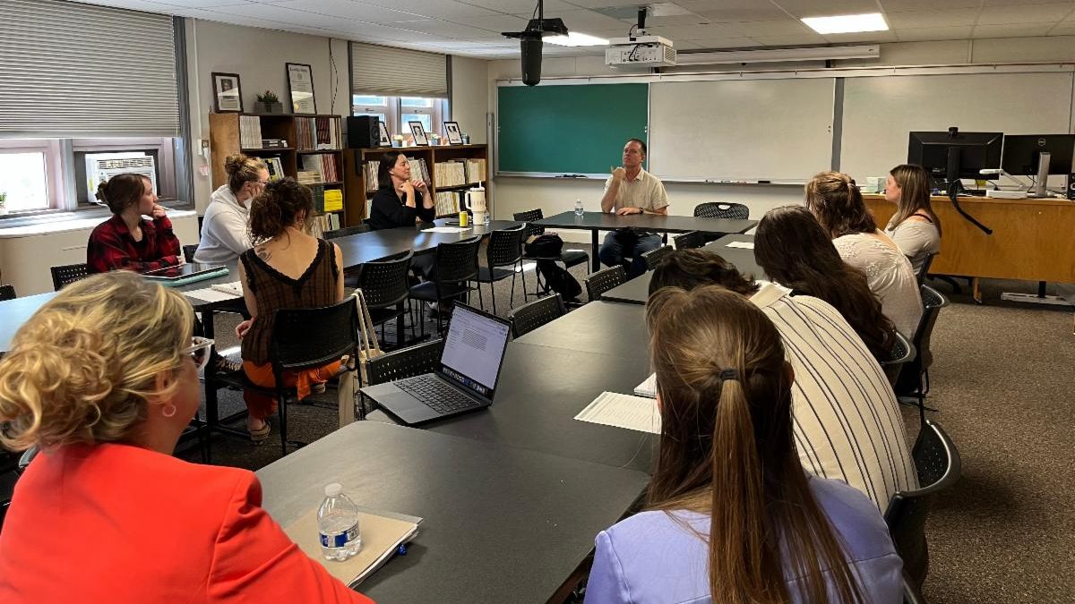 Nate Eaton sits at a table talking to students