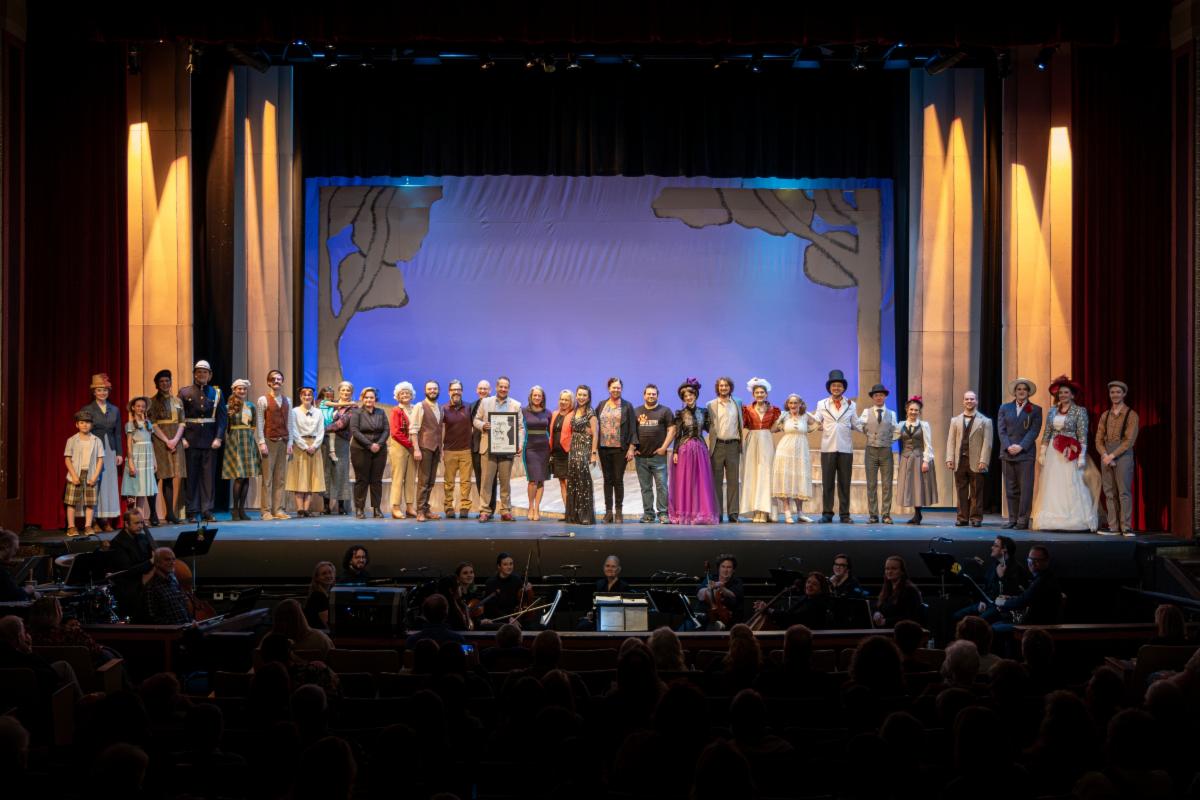 President Wagner stands on-stage with the cast and crew of Sunday in the Park with George. ISU musicians are in the orchestra pit.