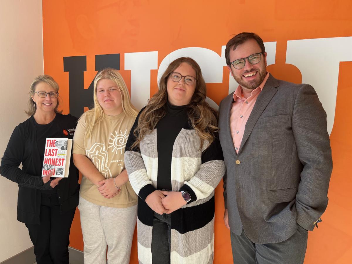 four people stand together for a photo in front of the wall with KISU on it