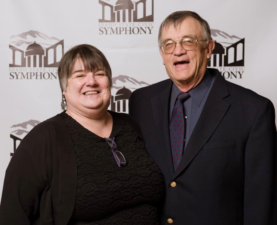 headshot of Grant and Donna Thomas, who smile in front of the Idaho State Civic Symphony logo backdrop