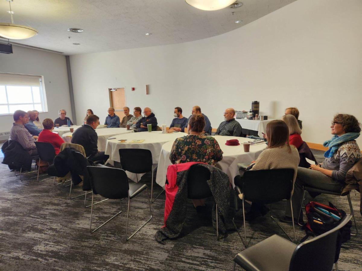 A group of faculty members meet at a conference table to discuss ideas