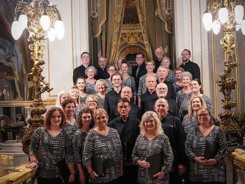 A group of people standing in an ornate opulent interior with decorative lighting and architecture.