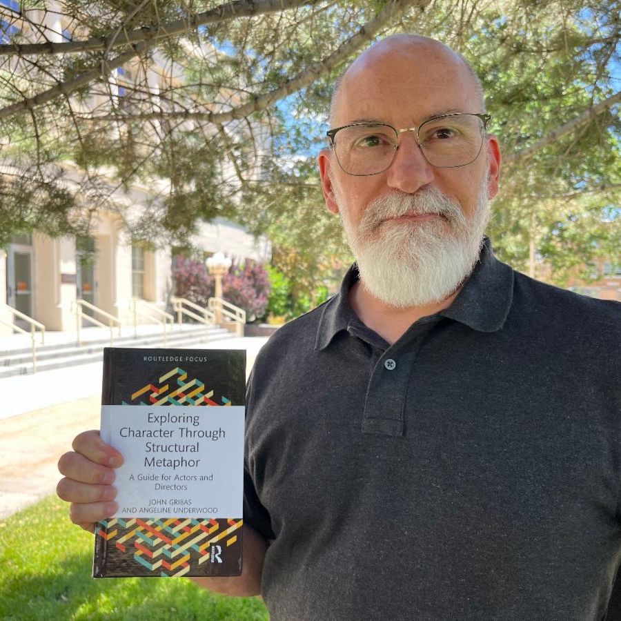 John Gribas stands outside. He holds up a copy of his book.