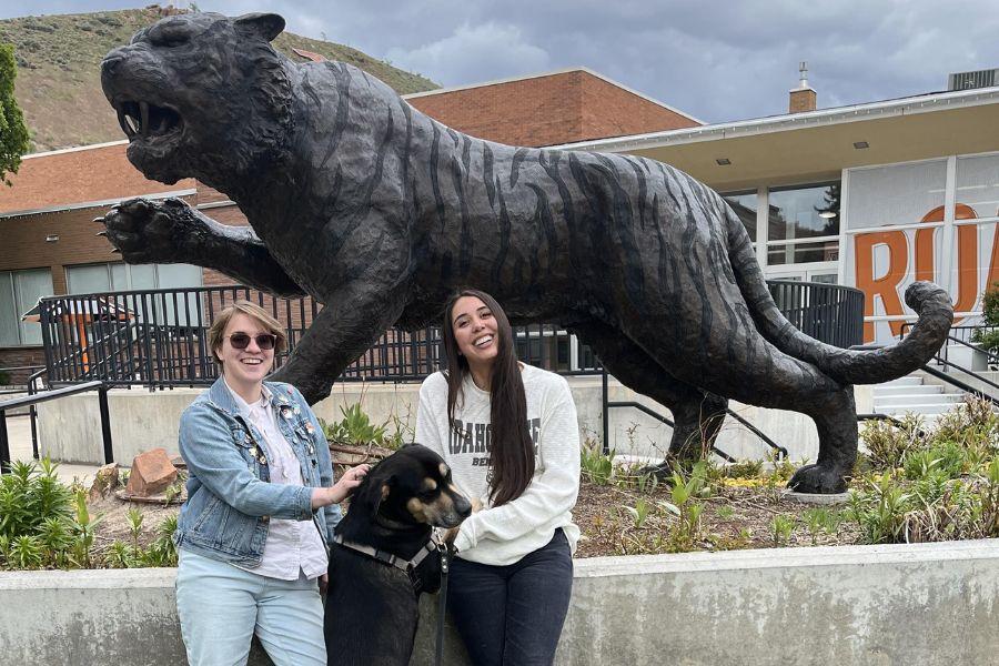 Joules and Julia stand at the Bengal statue with a black lab dog in between them.