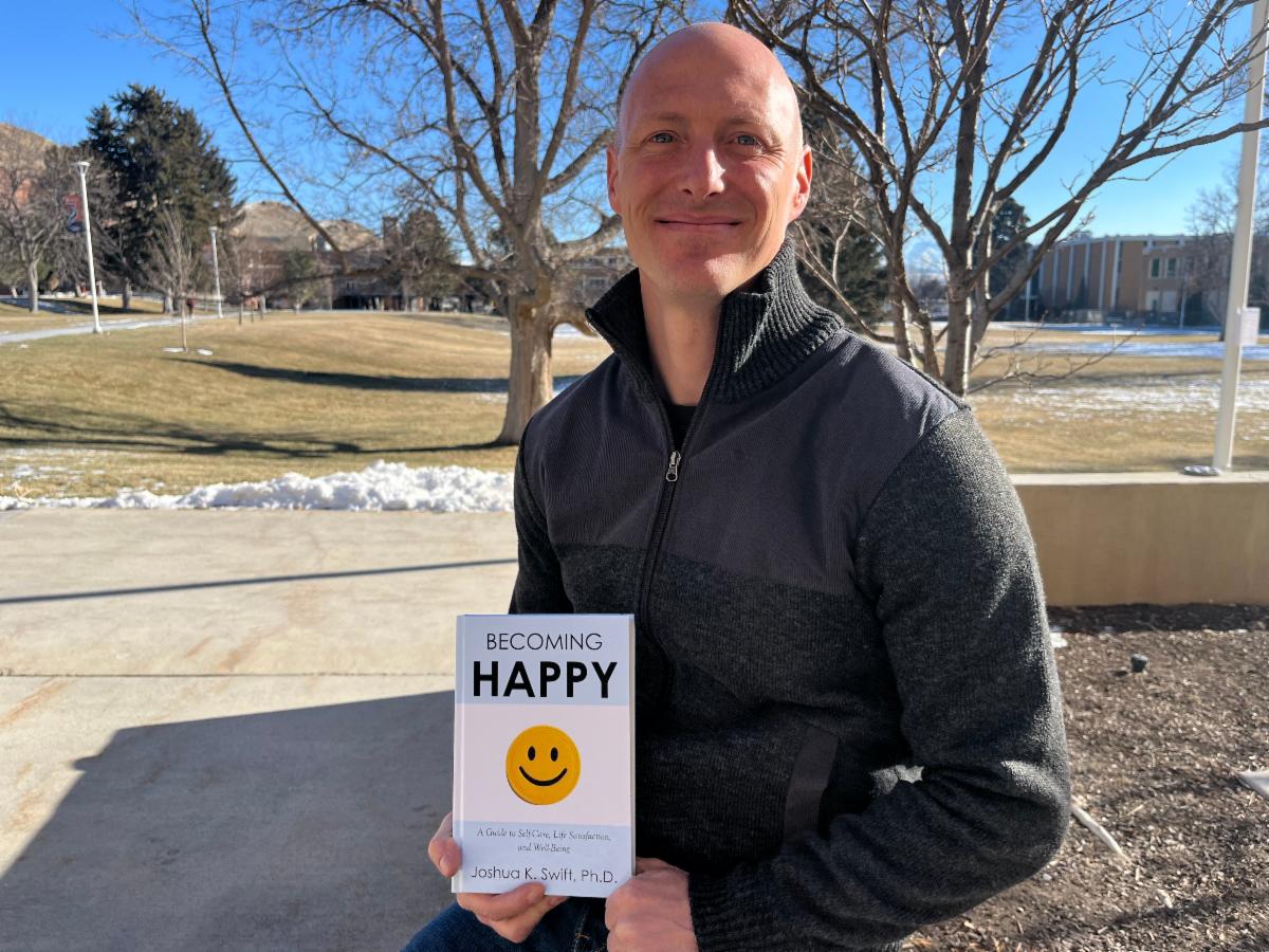 Joshua Swift holding his book Becoming Happy