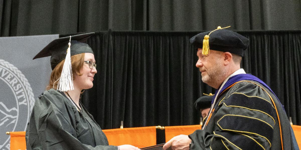 Student on stage accepts diploma from Pres. Satterlee