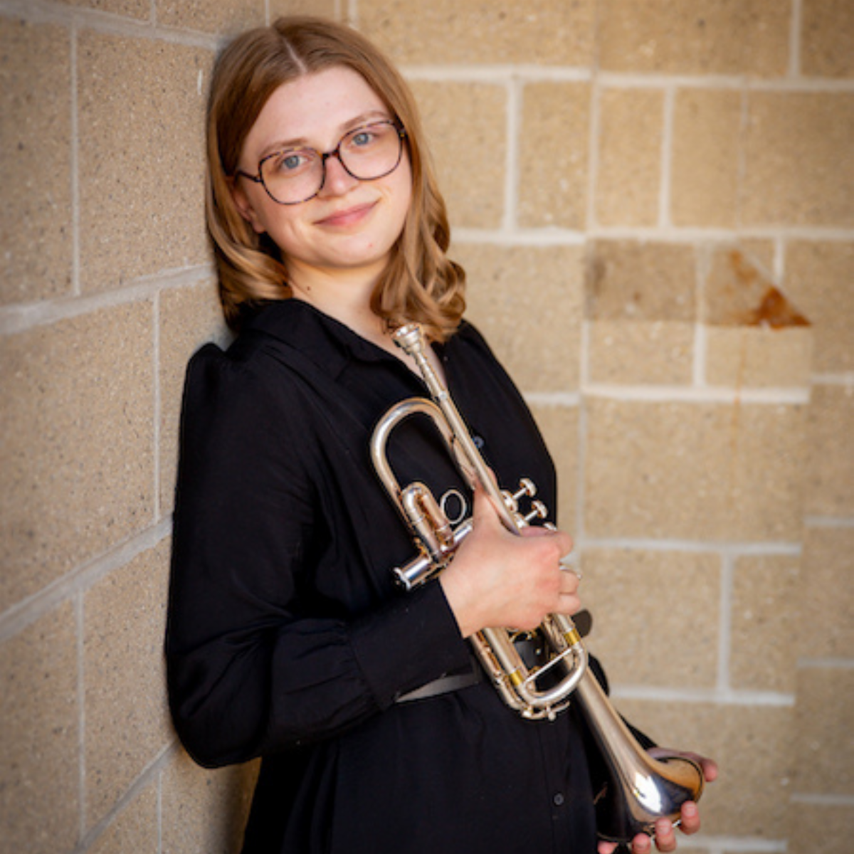 Headshot of MacKenzie. She is holding a silver trumpet.