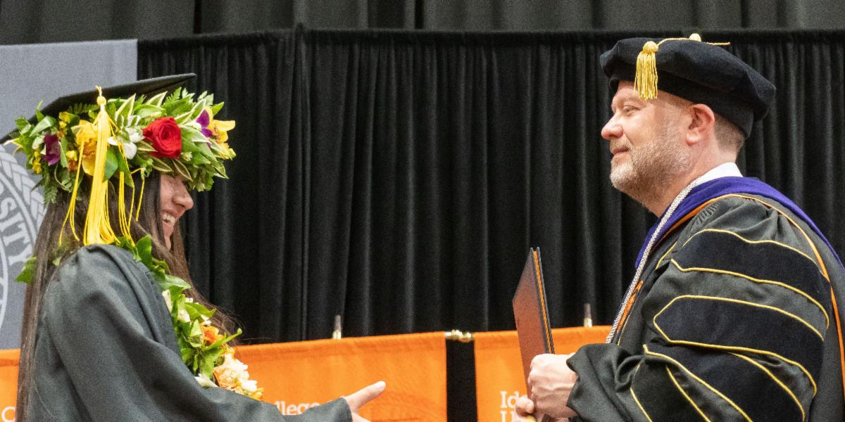 Graduate walks across the stage and accepts diploma from President Satterlee