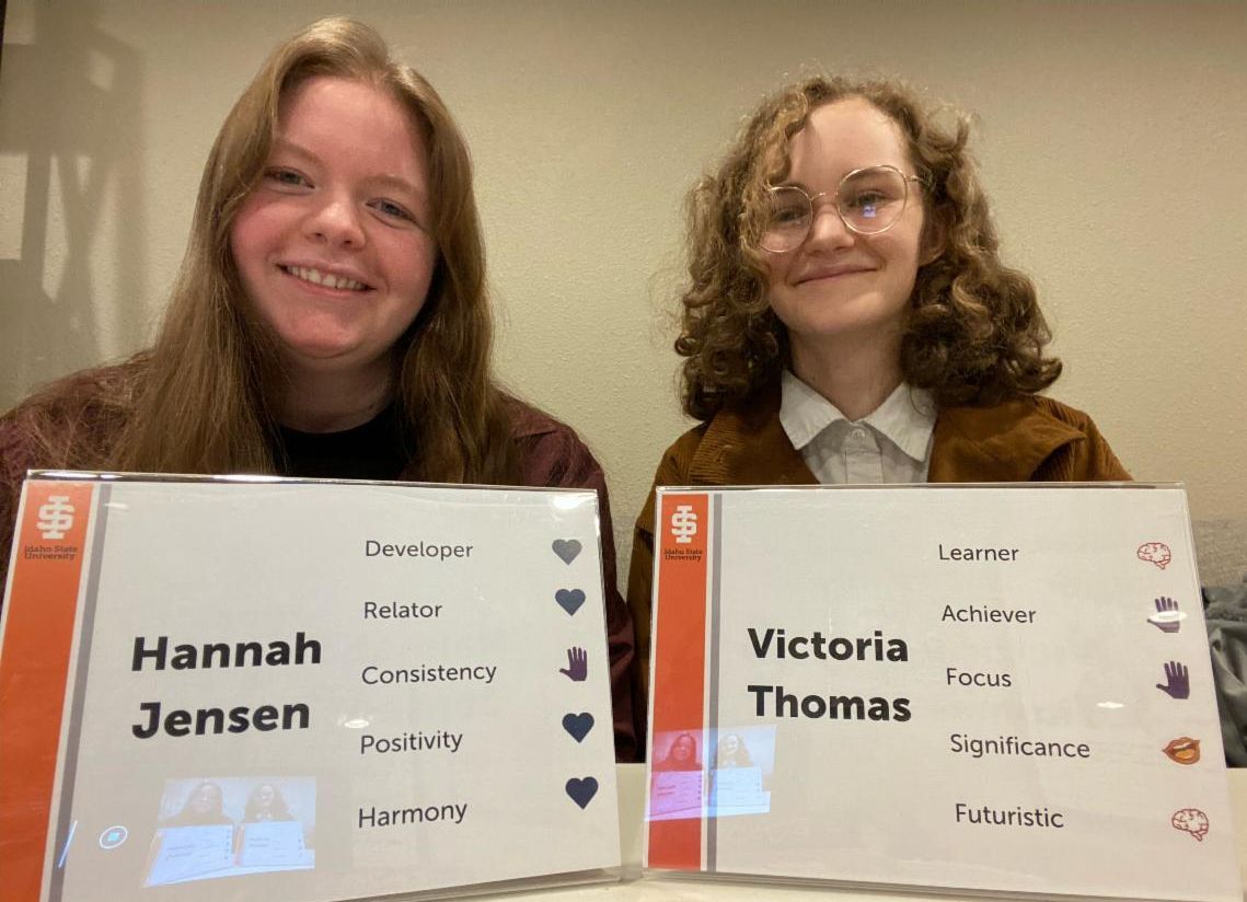 2 students sitting with nameplates that have strengths on them