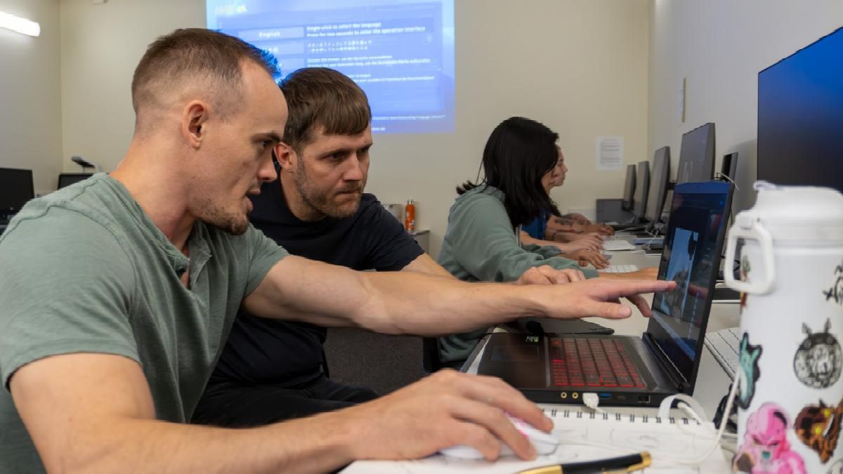 Art professor Shawn Edrington sits with a digital media art student. They are working together on a computer art design.