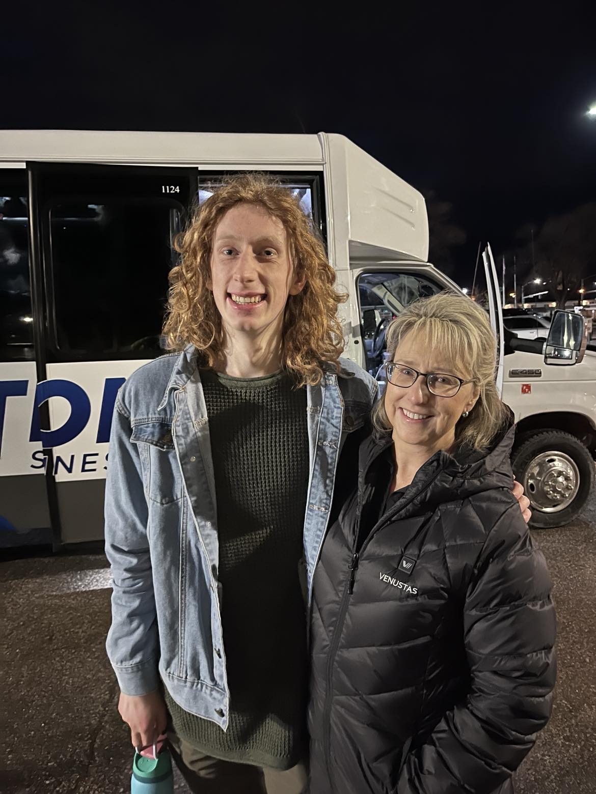 ISU student Parker Carlson stands with Dean Kandi Turley Ames in front of the bus that will take him to Spokane for a choir performance