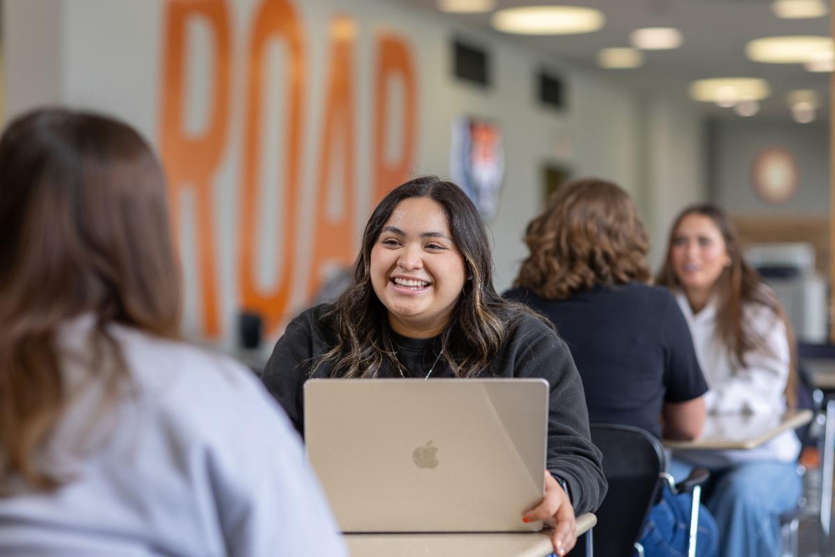 Students in the Student Union Building chat at tables