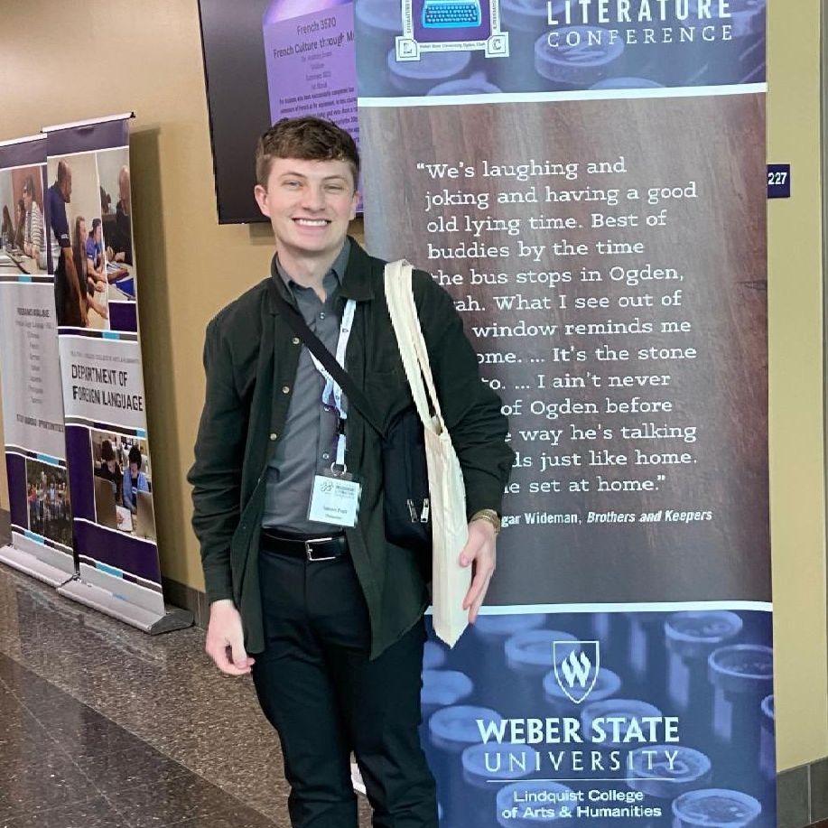 Tanner Pratt standing in front of a conference banner at Weber State