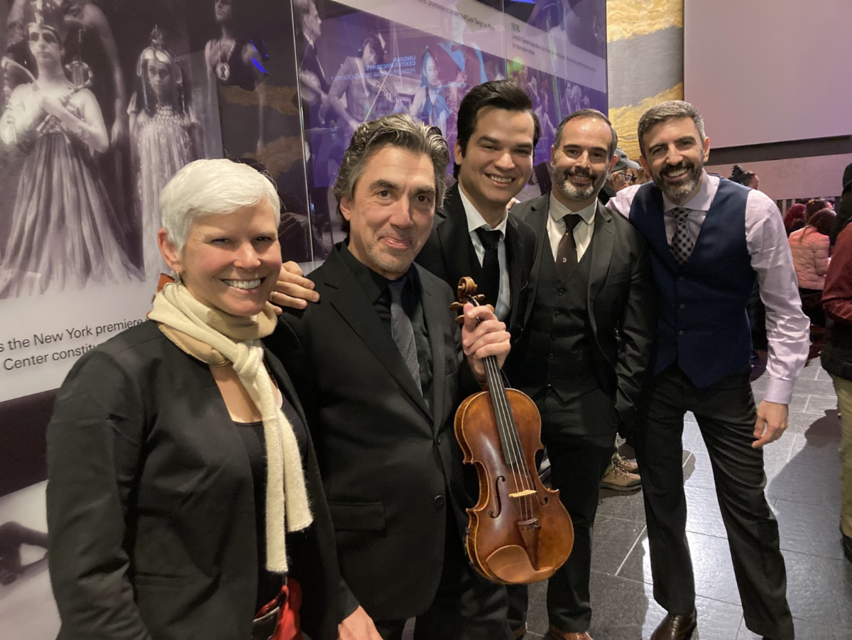 Nell Flanders and the Pedro Giraudo Tango Quartet pose for a photo together. Pedro holds a violin. They are in concert black and smiling.