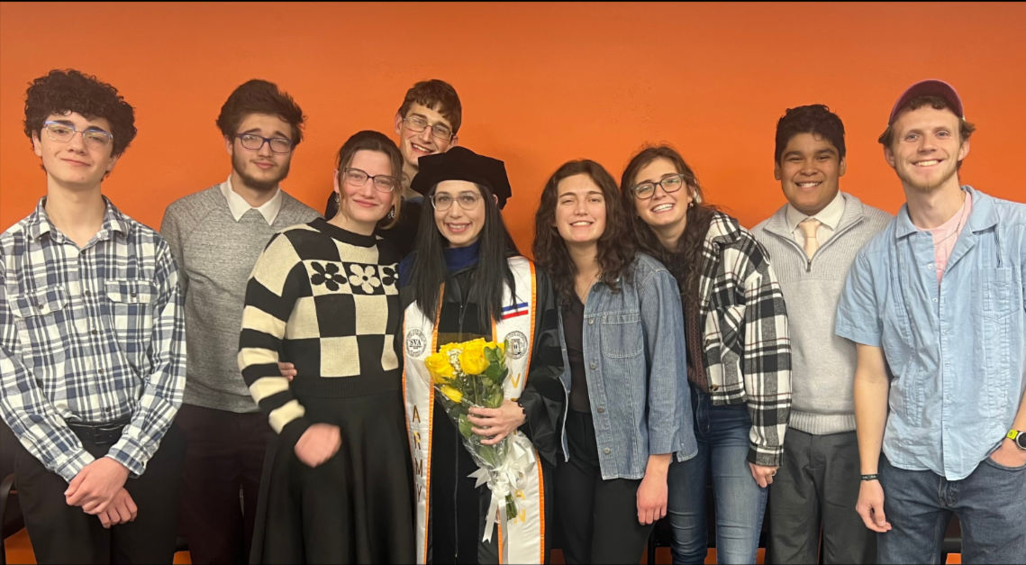 Mel Anderson wearing graduation attire surrounded by family and friends