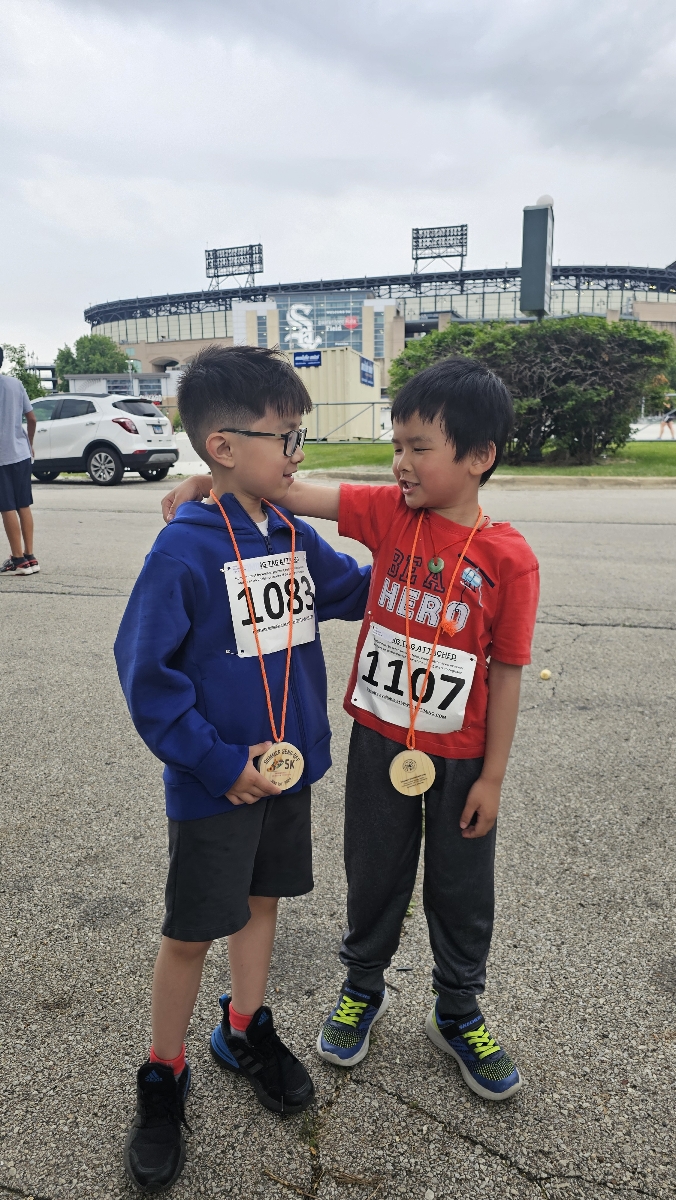 two young boys looking at each other wearing medals, guaranteed rate field is in the background.