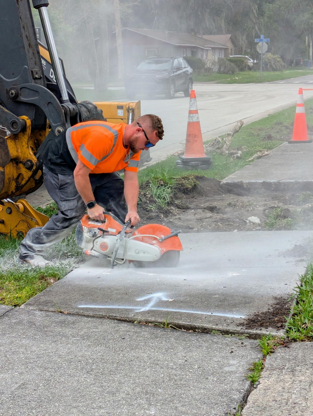 Public Works employee cutting into a sidewalk for repairs