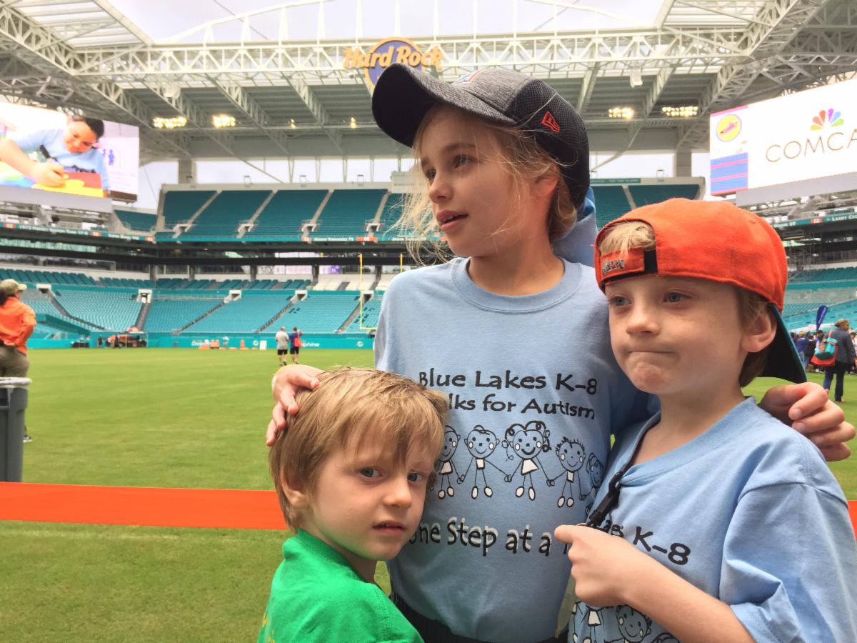 Photo of the three Sando children in front of a baseball field