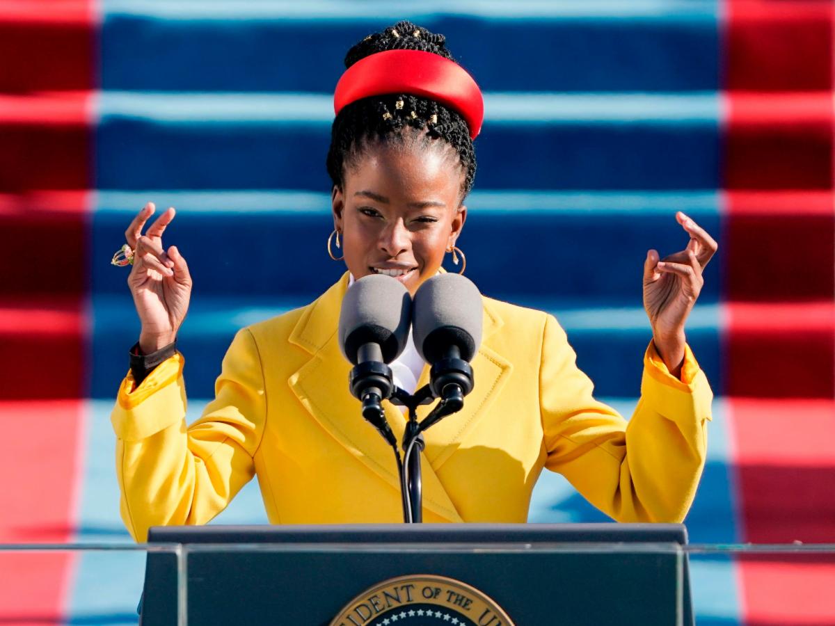 Amanda Gorman speaking at the inauguration with her hands held up.