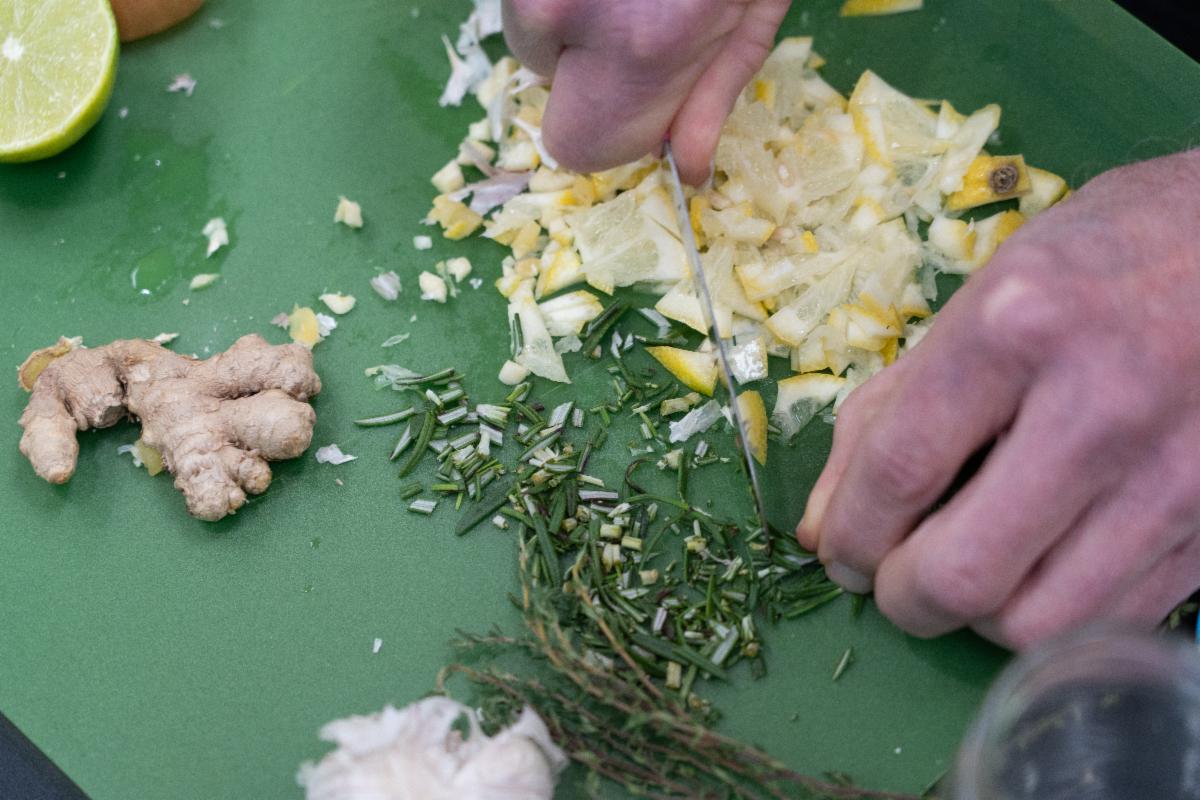 Hands cut herbs on a green cutting board