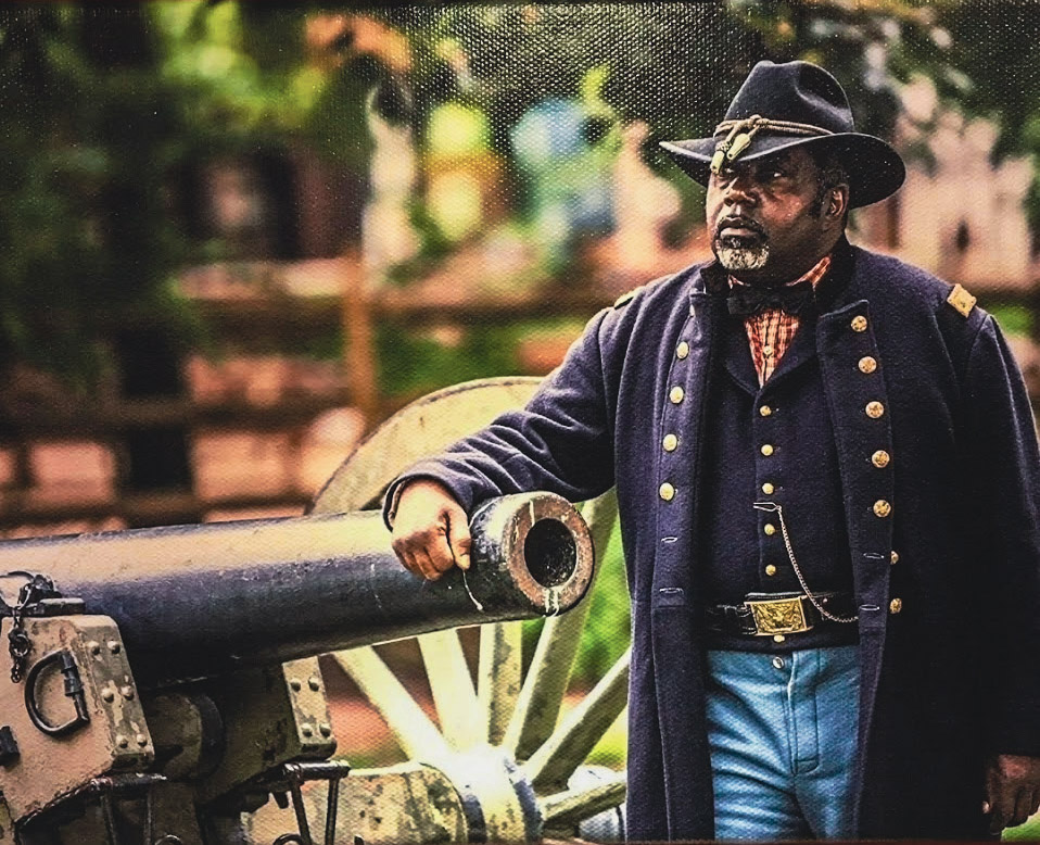 A man in historic clothing poses by a cannon
