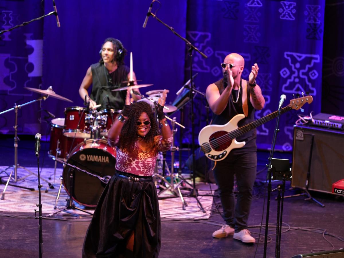 A band plays on a stage lit with purple lights