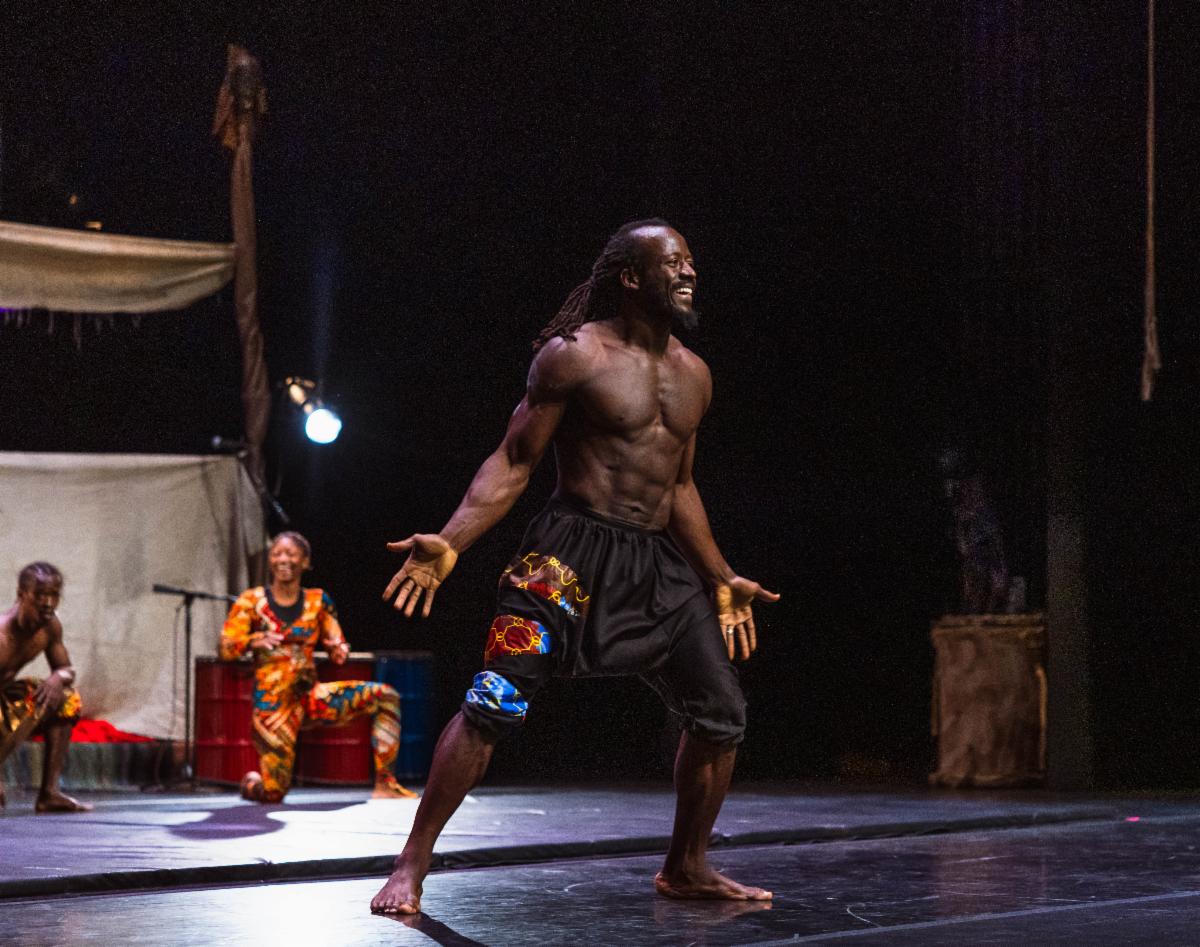 A man smiles and stands with palms down on a stage