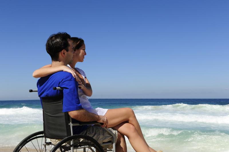 couple in love  woman and husband in wheelchair on the beach