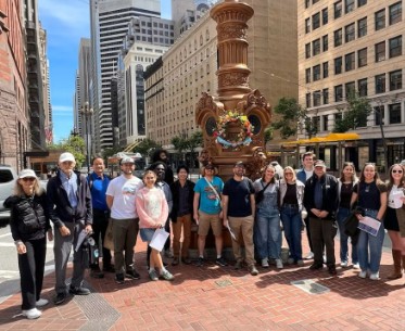 Members of SEAONC gather for a tour on the streets of San Francisco. They are standing in a row, smiling.