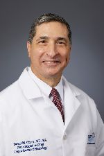 Man with short graying hair in a white doctor's coat, smiling