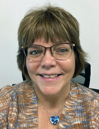 Woman with short hair, bangs, and glasses, smiling