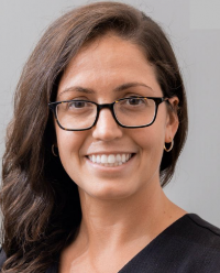 White woman with glasses and long brown hair swept to the side
