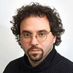 Brunette man with curly hair, glasses, and beard