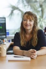 Laura Bohn, woman at her desk looking at camera