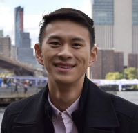 Young Asian man smiling in front of a cityscape