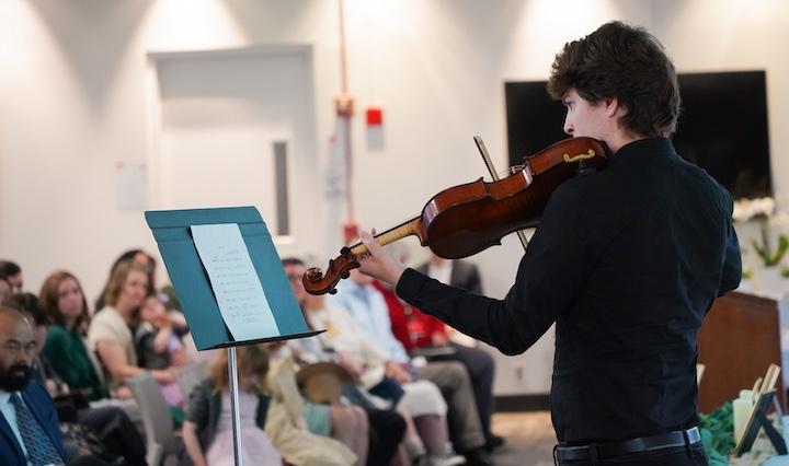 A man plays the violin for a group of people