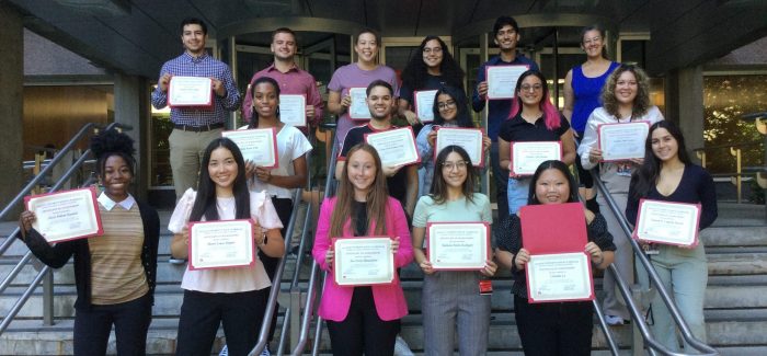 A group of students stand on the steps in front of BUSM holding certificates