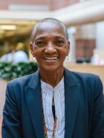 Thea James, a black woman with close shaved hair, smiling