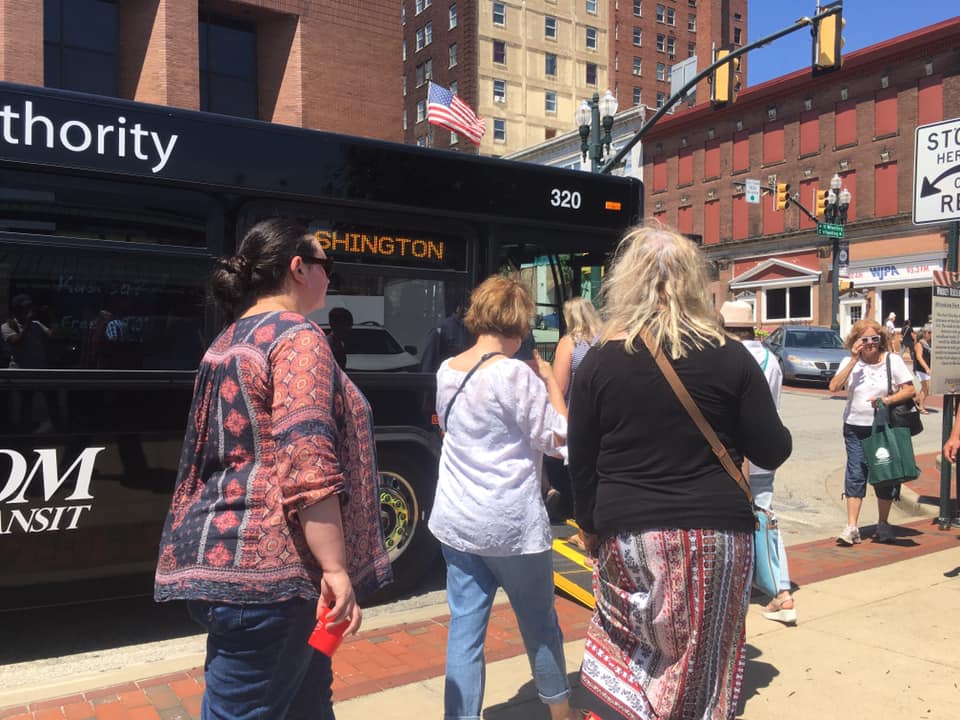 Women walking by parked bus at an outdoor event