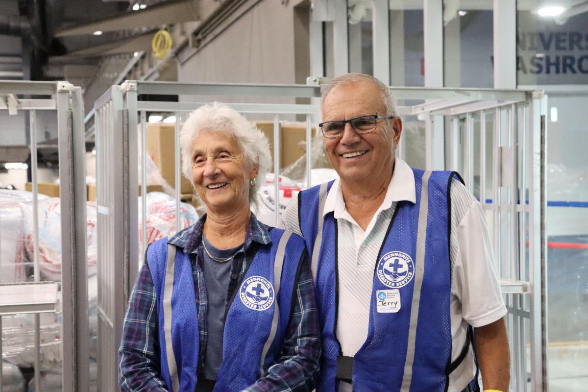 Two volunteers stand together in vests in an evacuee reception centre.