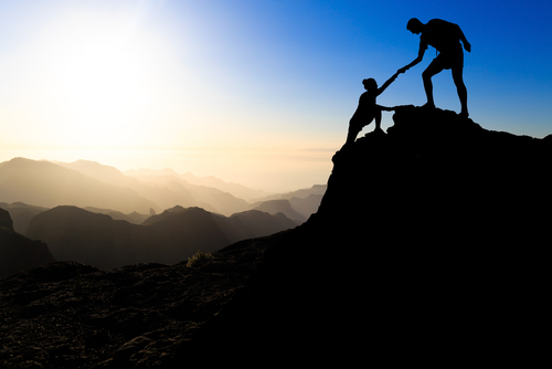 Teamwork couple hiking help each other trust assistance silhouette in mountains_ sunset. Team of climbers man and woman hiker helping each other on top of mountain_ climbing trust beautiful landscape.