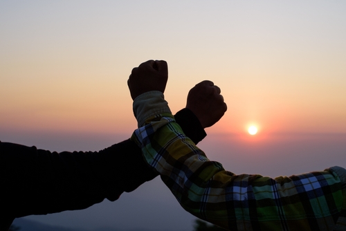 Silhouette close-up of Teamwork helping hand trust help. Success in mountains. Hikers celebrate with hands up. Help each other on top of mountain and sunset landscape.