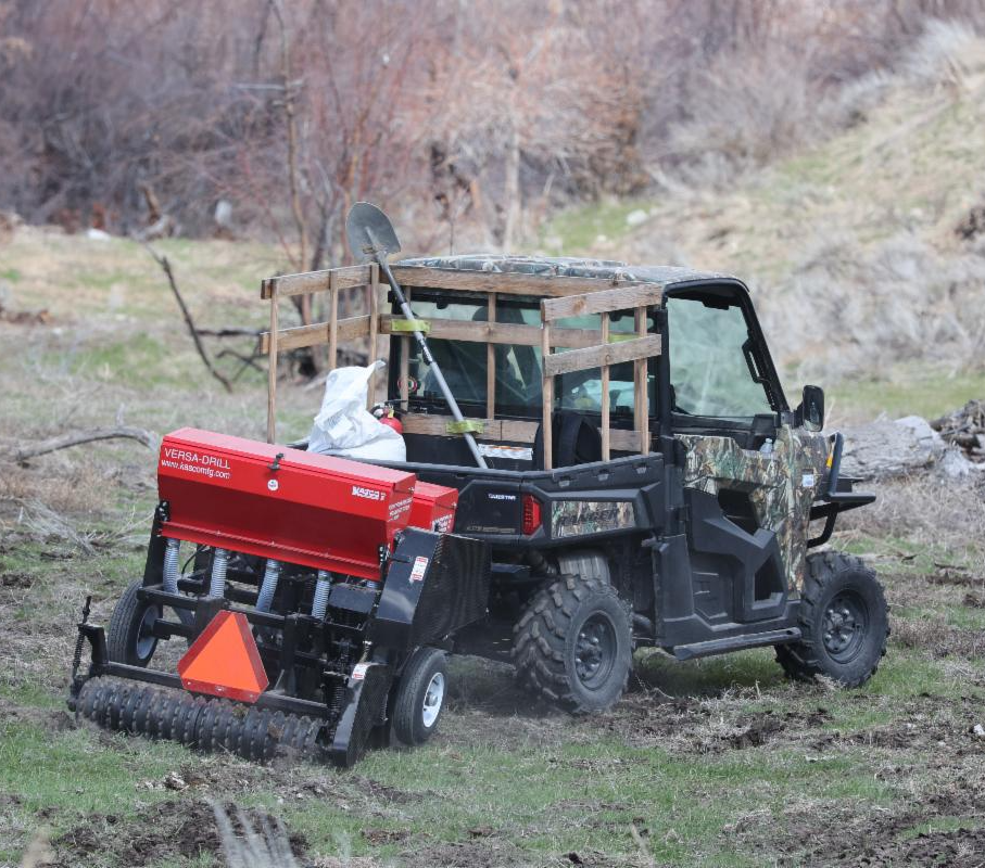 Red no-till seed drill being pulled by a black UTV