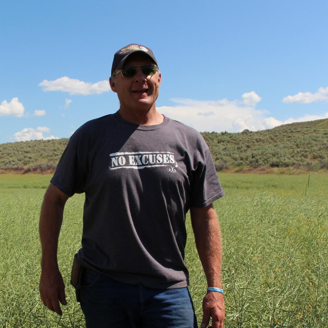 Previous board member, Edd Townsend, smiling in a field and wearing a t-shirt labeled "no excuses."