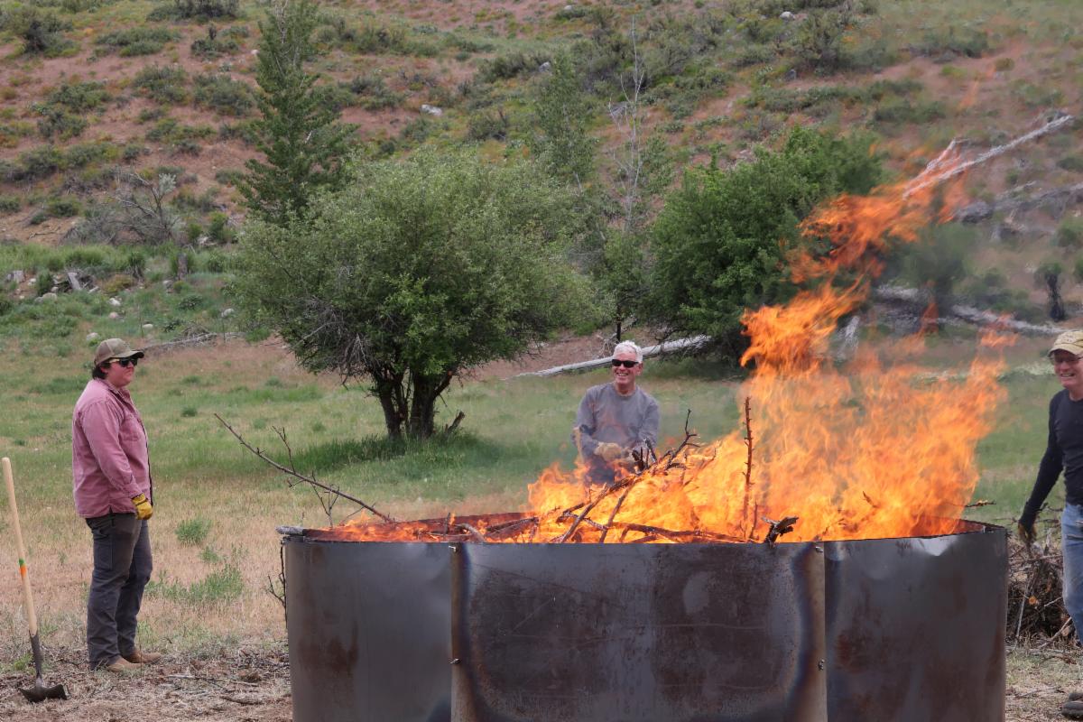 Okanogan CD hosting a biochar event, pictured managing active flames inside a large biochar kiln. 