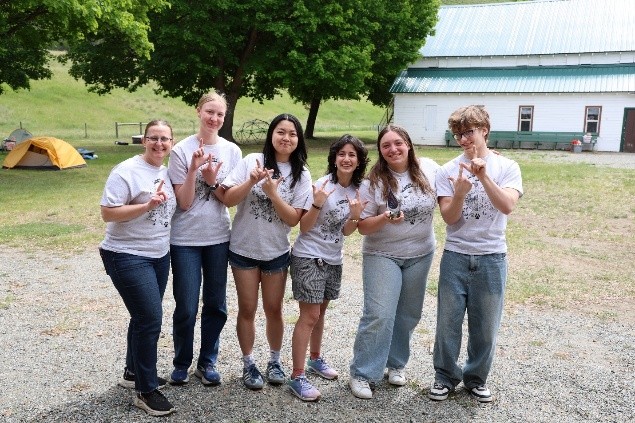 The winning Envirothon team of 6 students smiling in a group and holding up the number 1 signal.